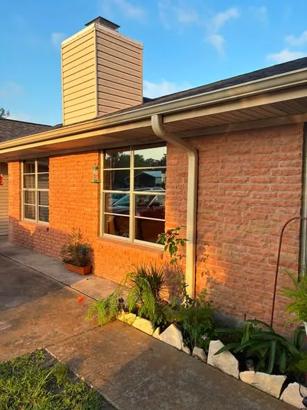 Fresh seamless gutter and downspout on a brick home at golden hour