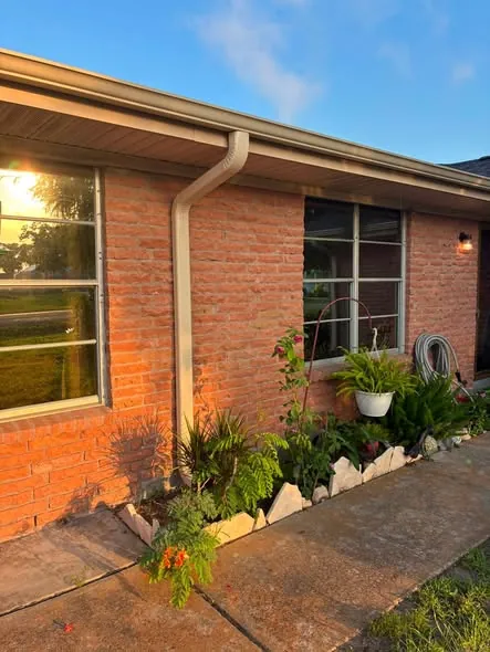 Downspout installed beside a garden bed on a brick house
