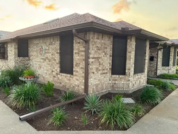 Wide view of brown seamless gutters wrapping a brick home
